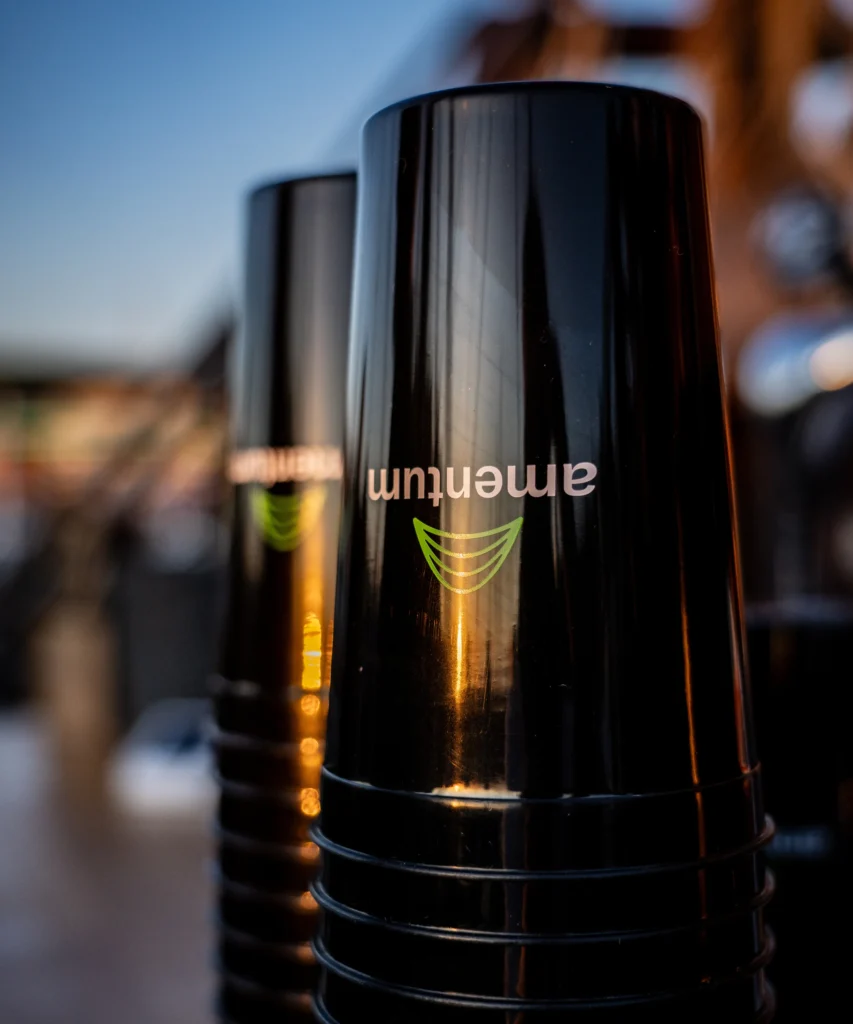 Stack of branded Amentum reusable cups on a bar at sunset
