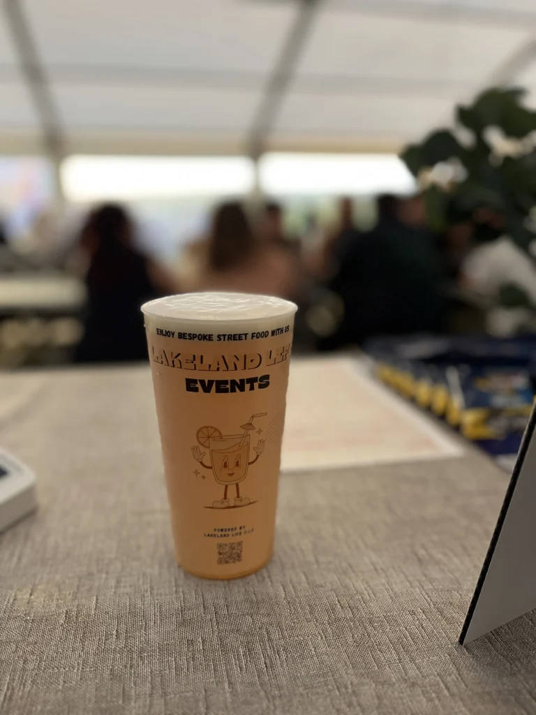 Reusable Lakeland Events drinks cup with blurred crowd in the background.