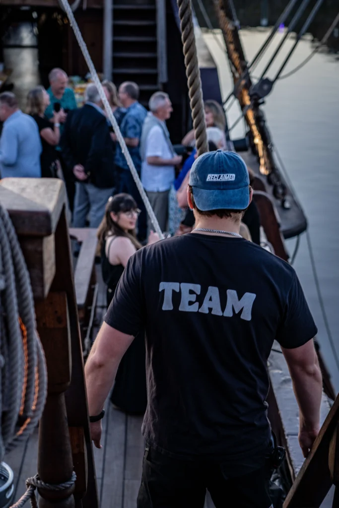 male with team written on the back of his shirt at a corporate boat event with people in the background